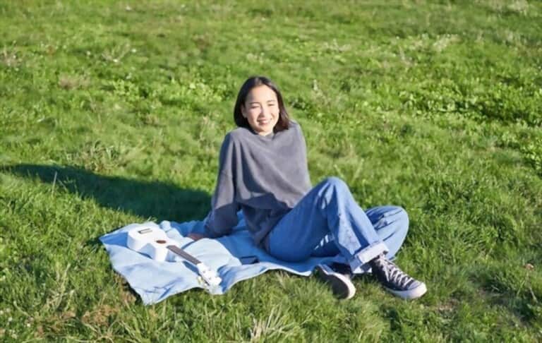 a young girl wearing blue jeans and warm sweater sitting on the grass a young girl wearing blue jeans and warm sweater sitting on the grass