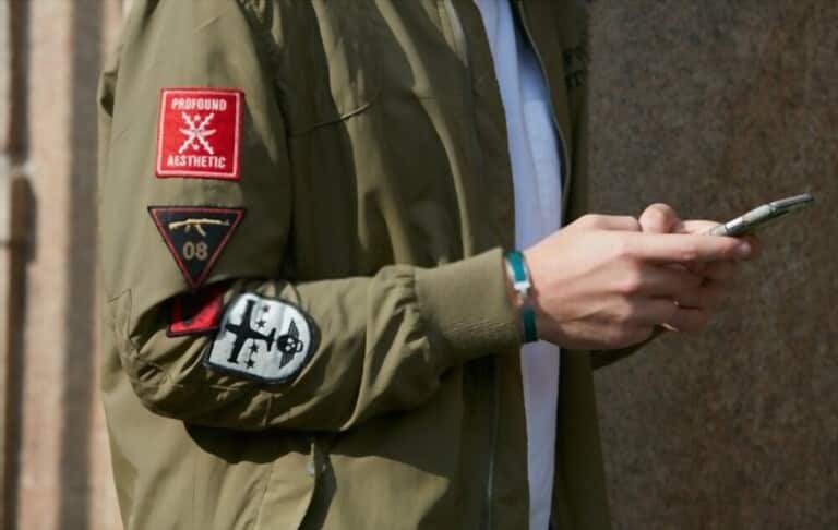a man with bomber jackets using smartphone near the wall a man with bomber jackets using smartphone near the wall