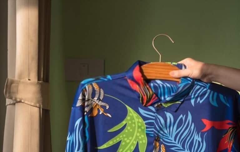 hand holding Hawaiian shirt on the bedroom background hand holding Hawaiian shirt on the bedroom background