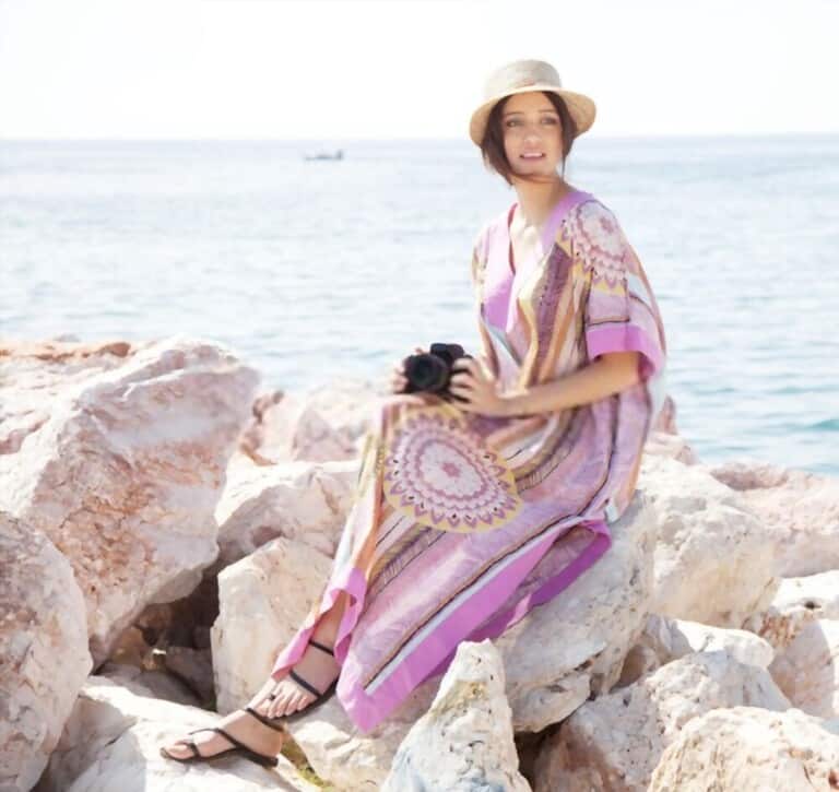 a young girl wearing caftans dress, sunhats with sandals sitting on the cliff near bech  a young girl wearing caftans dress, sunhats with sandals sitting on the cliff near bech