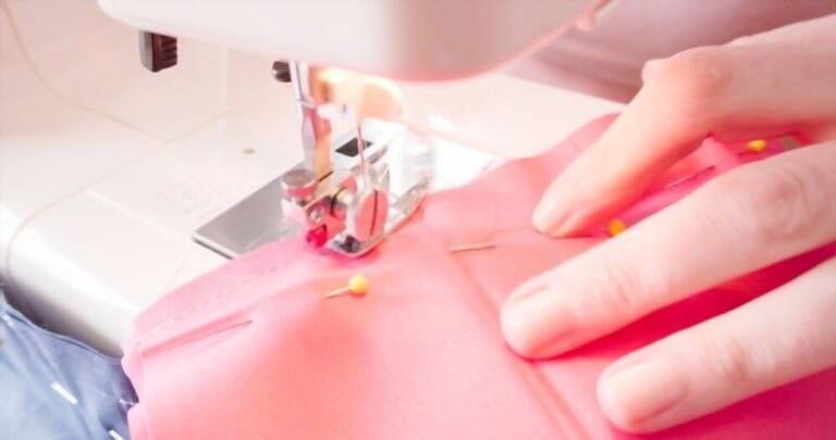 woman sewing cloths with pins fixed to the fabric woman sewing cloths with pins fixed to the fabric