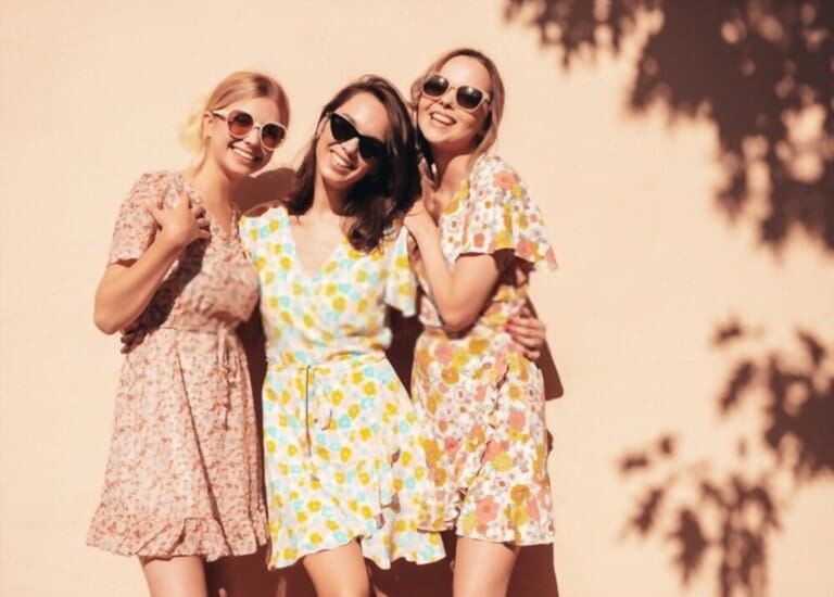 Three young beautiful smiling hipster female in trendy summer dresses clothes. Sexy carefree women posing in the street. Positive models having fun, talking, chatting. Going crazy. In sunglasses