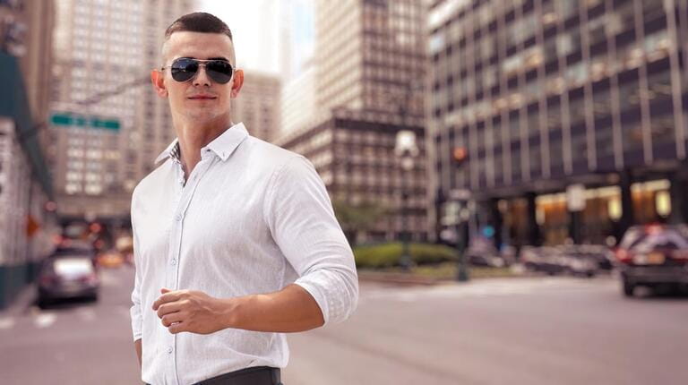 Gorgeous stylish young man wearing fashionable shirt and sunglasses. City style.