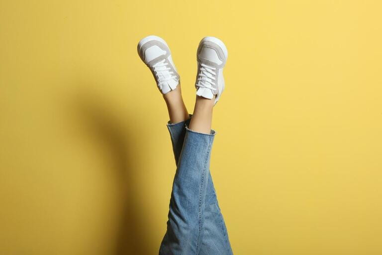 sneakers on female legs on a colored background. sneakers on female legs on a colored background.