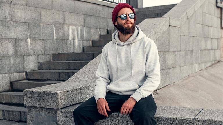City portrait of handsome hipster guy with beard wearing gray blank hoodie or hoody with space for your logo or design. City portrait of handsome hipster guy with beard wearing gray blank hoodie or hoody with space for your logo or design.