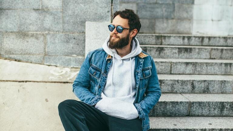 City portrait of handsome hipster guy with beard wearing gray blank hoodie or hoody with space for your logo or design.