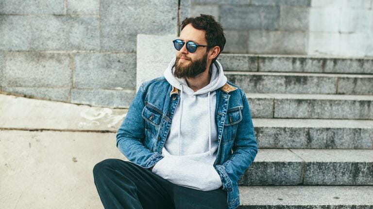 City portrait of handsome hipster guy with beard wearing gray blank hoodie or hoody with space for your logo or design. City portrait of handsome hipster guy with beard wearing gray blank hoodie or hoody with space for your logo or design.