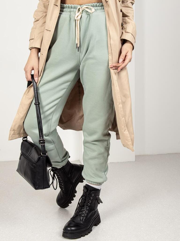 Woman in green pants. Insulated clothing for winter. Sports or casual wear. Pants, trench coat and boots Woman in green pants. Insulated clothing for winter. Sports or casual wear. Pants, trench coat and boots