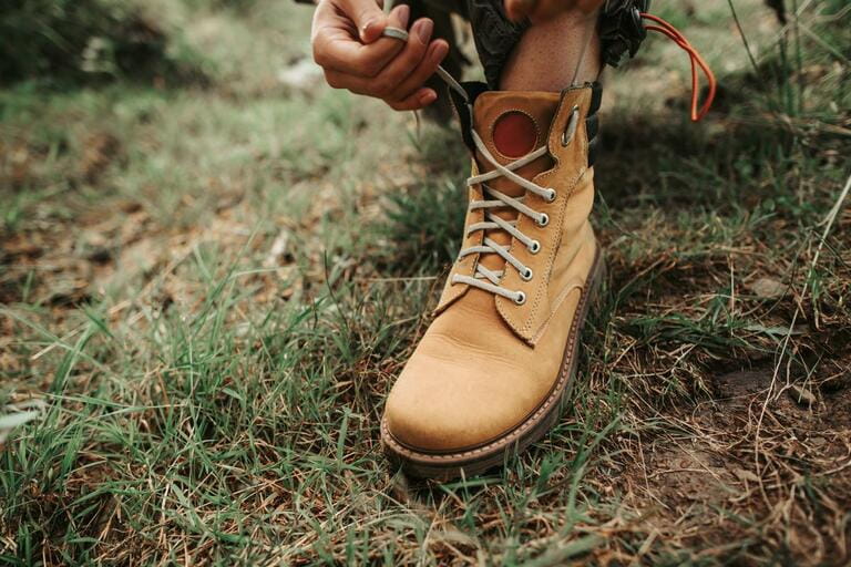Almost ready. Close up of stylish yellow boot on female leg. Lady standing on the grass Almost ready. Close up of stylish yellow boot on female leg. Lady standing on the grass