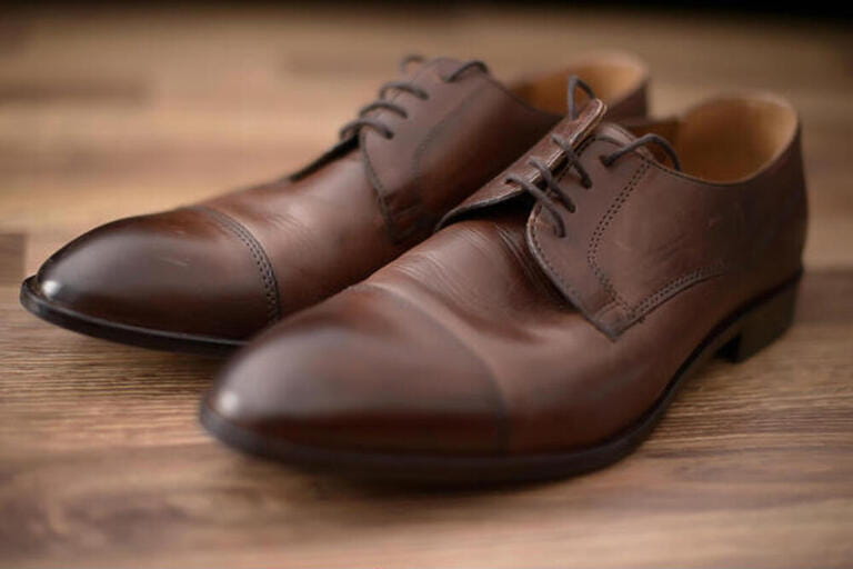 Elegant, used brown leather male shoes set on a brown wooden table