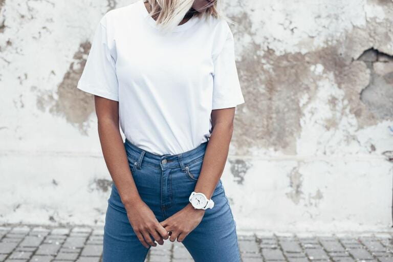 Hipster girl in white t-shirt and jeans pretending on rough street wall, minimalist urban clothing style, mockup for tshirt print shop