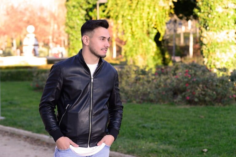 Young man in the park wearing a casual outfit and a slim leather jacket Young man in the park wearing a casual outfit and a slim leather jacket