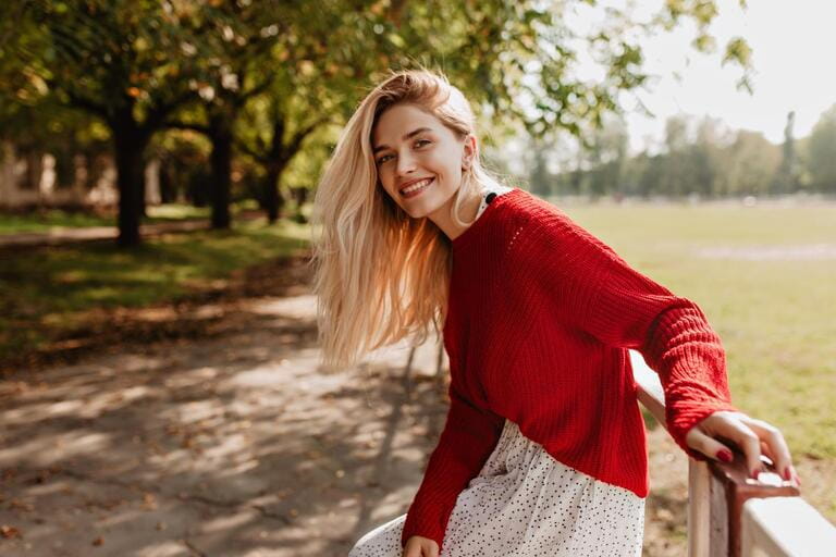 Smiling blonde woman laughing on cheerful street. Lovely young girl feels happy in the autumn park.