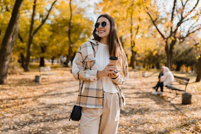 attractive young woman walking in autumn park with coffee wearing checkered coat, sunglasses, happy mood, fashion style trend attractive young woman walking in autumn park with coffee wearing checkered coat, sunglasses, happy mood, fashion style trend