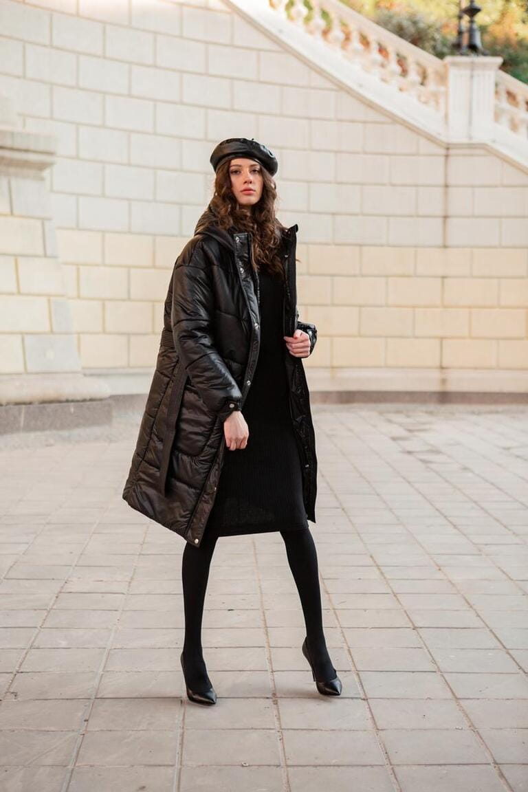 stylish woman posing in winter autumn fashion trend black puffer coat and leather hat beret in old beautiful street wearing high heel shoes