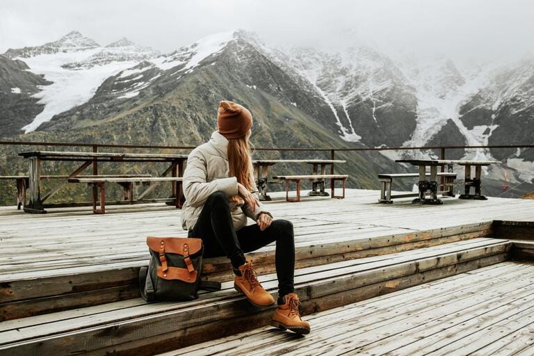 Girl traveler with backpack enjoy mountain nature sitting on wooden bridge Girl traveler with backpack enjoy mountain nature sitting on wooden bridge