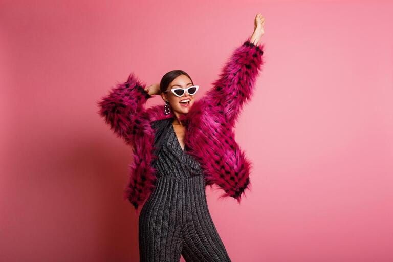 Fabulous brunette girl dancing in short pink faux fur coat in studio. Party and winter trends concept. Fabulous brunette girl dancing in short pink faux fur coat in studio. Party and winter trends concept.