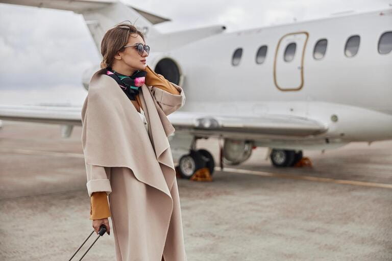 Mature business woman in coat near her jet in airport