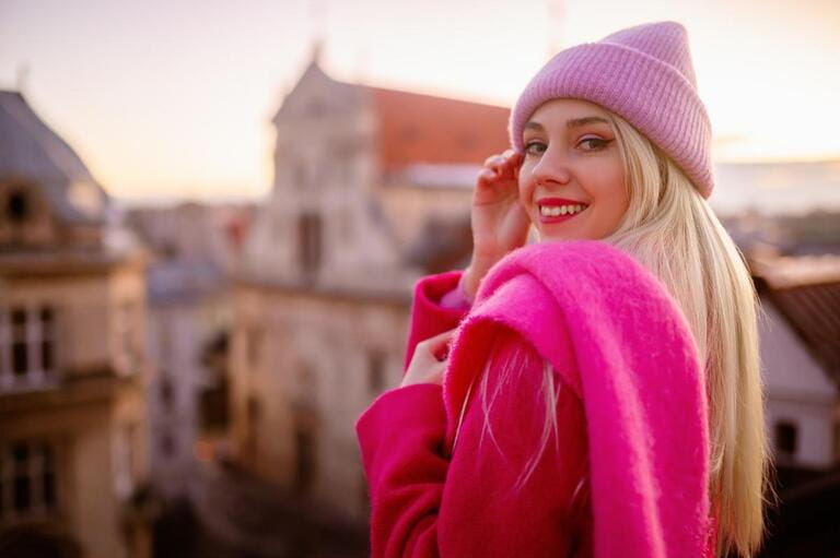 Happy smiling fashionable blonde woman wearing trendy knitted beanie hat, woolen scarf, coat, posing outdoor, with beautiful city view. Happy smiling fashionable blonde woman wearing trendy knitted beanie hat, woolen scarf, coat, posing outdoor, with beautiful city view.