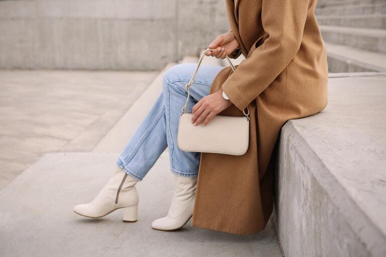 Stylish woman with trendy beige bag on stairs outdoors, closeup