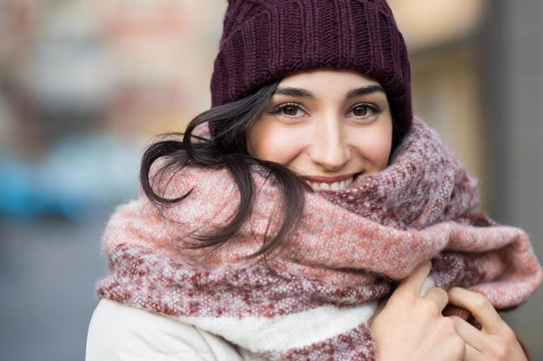 Close-up of face of a happy young woman enjoying winter wearing a scarf and hat. Smiling girl in a colorful shawl looking at the camera. Latin woman with knitted bordeaux hat and wool scarf Close-up of face of a happy young woman enjoying winter wearing a scarf and hat. Smiling girl in a colorful shawl looking at the camera. Latin woman with knitted bordeaux hat and wool scarf