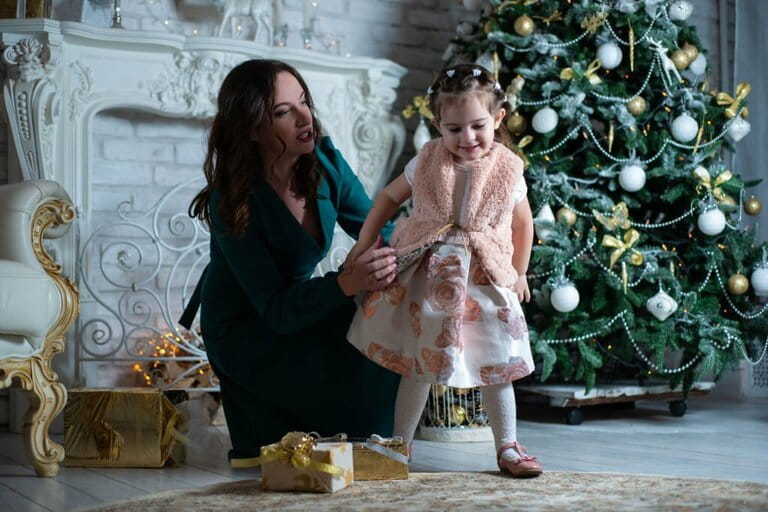 Merry Christmas and happy holidays. Mother and daughter have fun near the Christmas tree with gifts