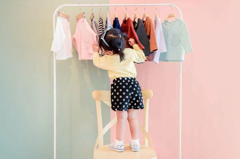 The soft focus of a two-year-old choosing her own dress from a rack of children's fabrics