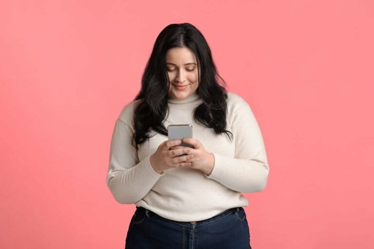 Plus size woman holding smartphone in hand, texting or reading messages