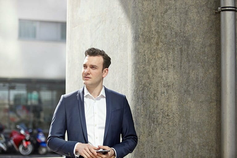 Mid adult businessman standing with smartphone, London, UK
