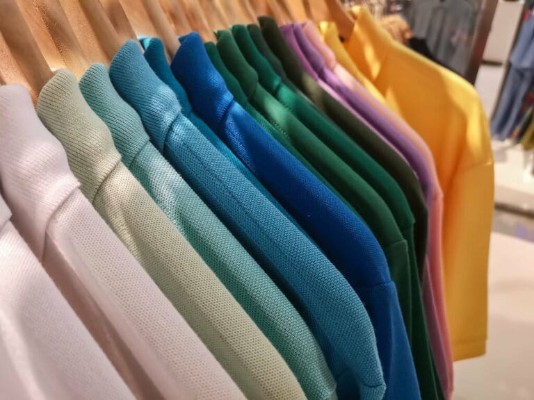 Men's multicolored polo shirts, in many shades of color, hang on racks in a department store. Men's multicolored polo shirts, in many shades of color, hang on racks in a department store.
