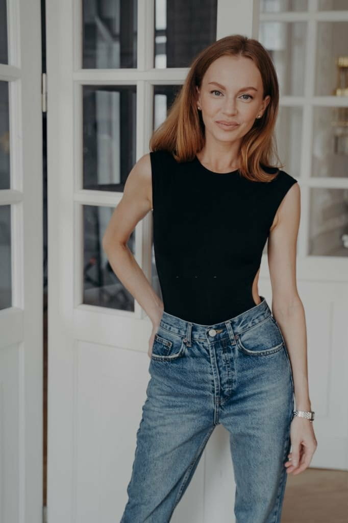 Portrait of a happy, confident young middle-aged woman. Lady is standing near the door window. Portrait of a happy, confident young middle-aged woman. Lady is standing near the door window.