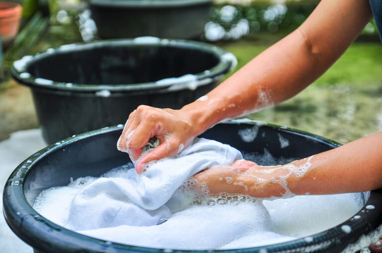 Female hand washing clothes in sink. Wash clothes by hand with detergent. The water will wash through the washing machine.