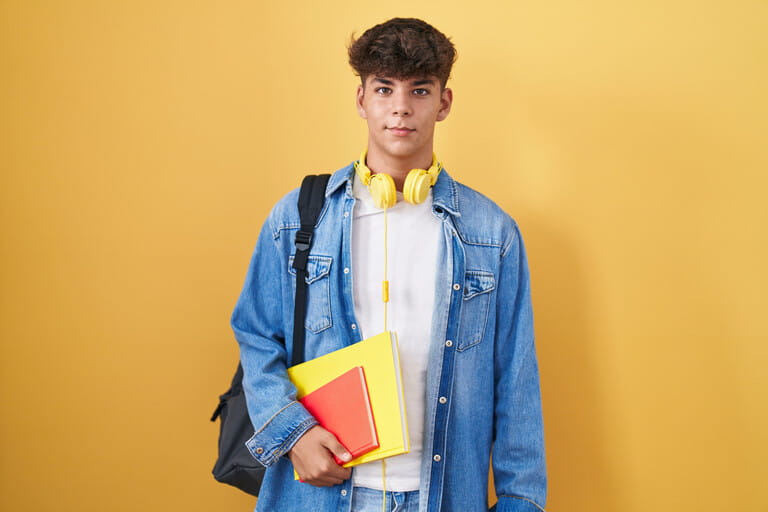 Hispanic teenager wearing student backpack and holding books with a happy and cool smile on face. lucky person.