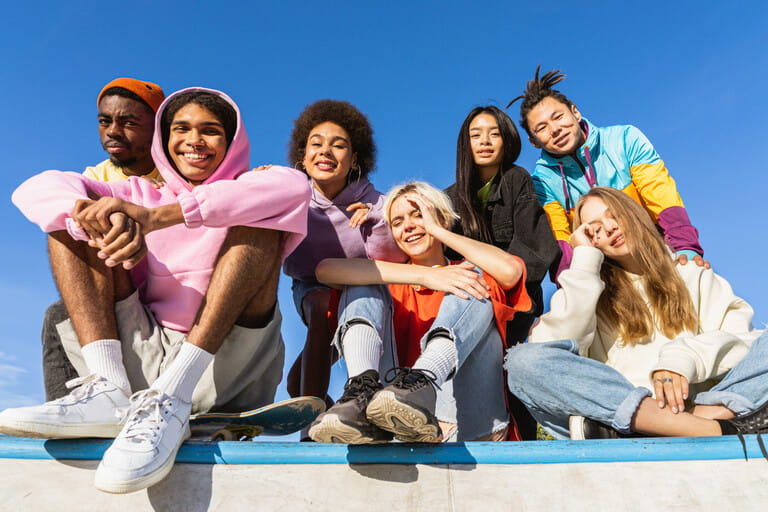 Multicultural group of young friends bonding outdoors and having fun - Stylish cool teens gathering at urban skate park