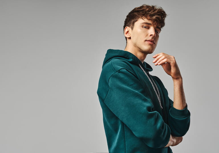 Handsome man in green hoodie isolated on gray background Handsome man in green hoodie isolated on gray background