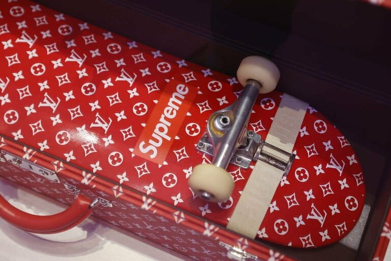 A trunk and a skateboard for Louis Vuitton and Supreme are displayed