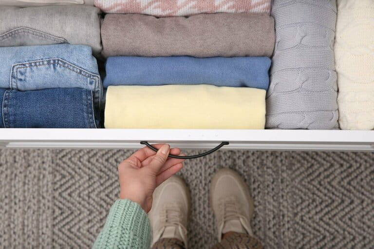 Woman opens a drawer with folded clothes in the house, looking from above.