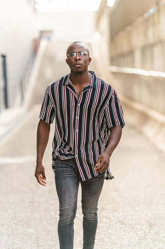 Vertical shot of a young sexy black man with a striped shirt and sunglasses