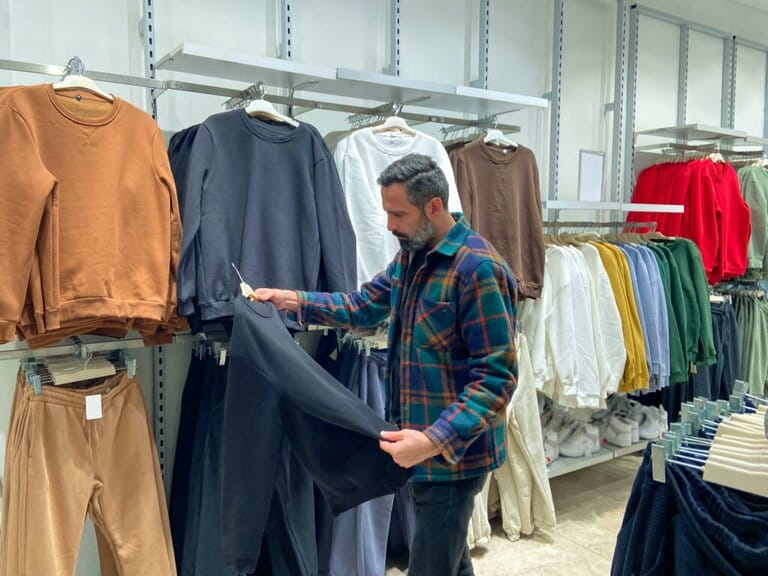 Man choosing clothes to buy in clothing store