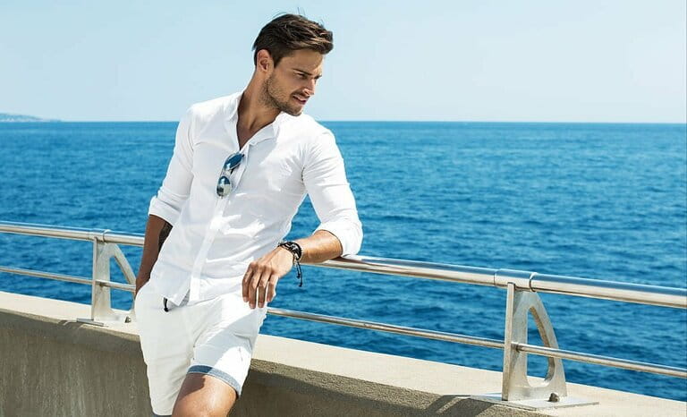 Handsome man wearing white clothes posing in sea landscape