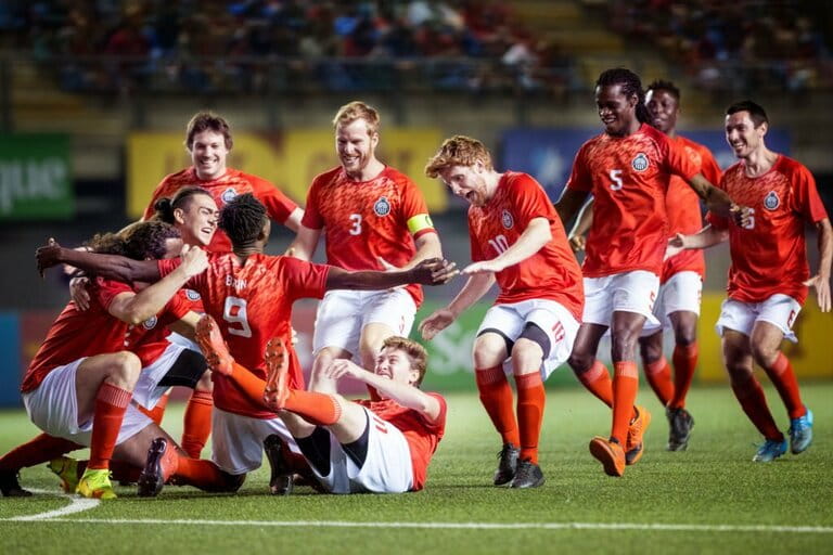 Ecstatic team of male soccer players run together and embrace their striker teammate to celebrate a goal  Ecstatic team of male soccer players run together and embrace their striker teammate to celebrate a goal