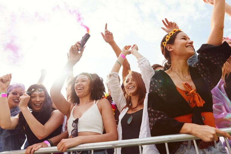 Spectators with smoke flares behind barriers dance and sing at outdoor festival enjoying music Spectators with smoke flares behind barriers dance and sing at outdoor festival enjoying music