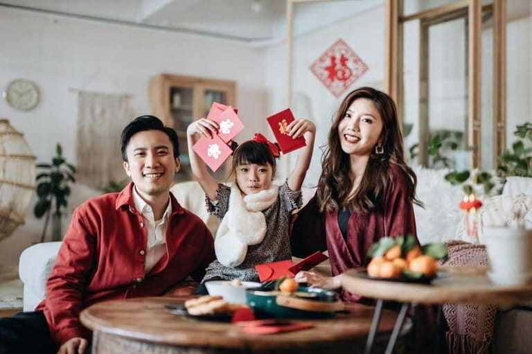 Happy Asian family holding red envelopes (lai see) and celebrating Chinese New Year together