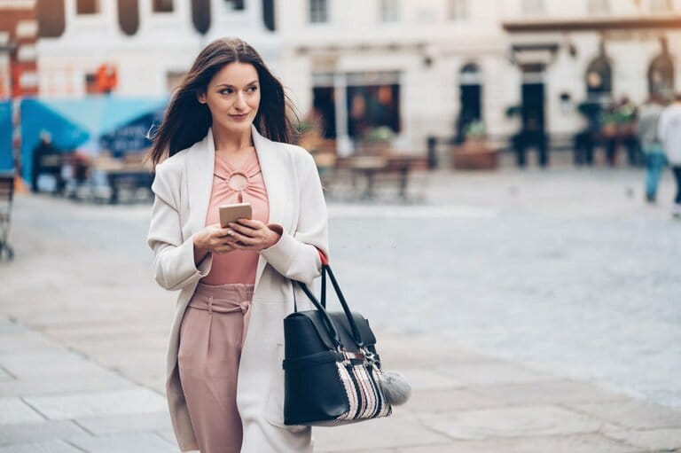 Fashionable woman holding phone and walking on the street Fashionable woman holding phone and walking on the street
