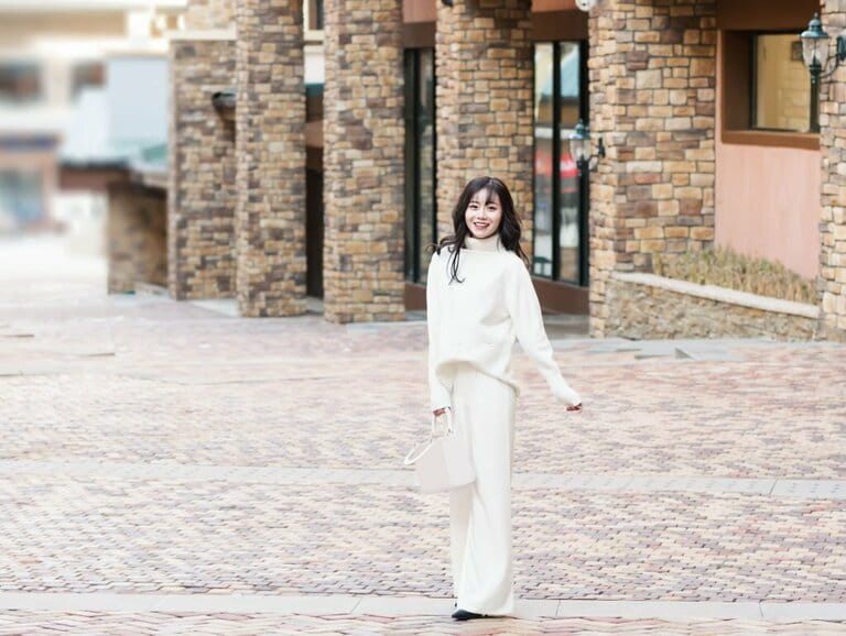 Trendy woman wearing white turtleneck and white trousers on the street Trendy woman wearing white turtleneck and white trousers on the street