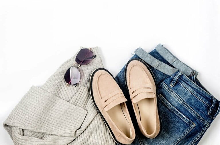 Blue jeans, oversize knitted Gery sweater, beige suede loafers or flats lie on a white background. Blue jeans, oversize knitted Gery sweater, beige suede loafers or flats lie on a white background.