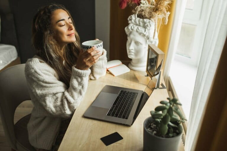 Young pretty woman enjoying morning coffee and working on laptop at home. Freelance business, distant job Young pretty woman enjoying morning coffee and working on laptop at home. Freelance business, distant job