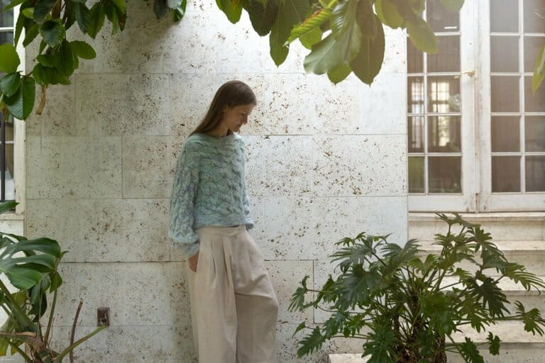 Woman with knitted sweater in green winter garden Woman with knitted sweater in green winter garden