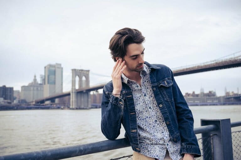Handsome man listening to earbuds against city skyline Handsome man listening to earbuds against city skyline