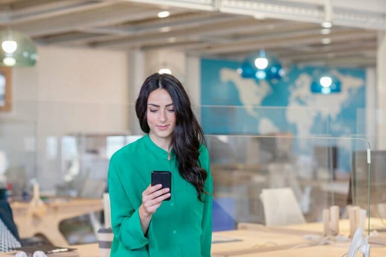 Female professional working on mobile phone while standing in office